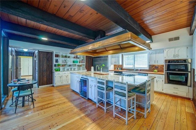 kitchen with beamed ceiling, a kitchen island, and white cabinets