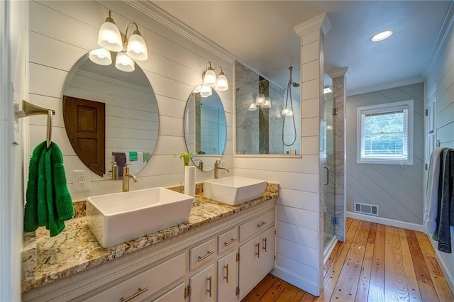 bathroom with a shower with shower door, ornate columns, ornamental molding, vanity, and hardwood / wood-style floors