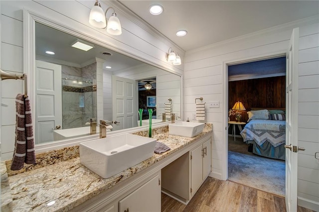 bathroom with a shower with shower door, ornamental molding, wooden walls, vanity, and hardwood / wood-style floors