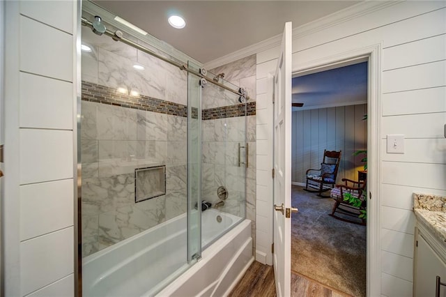 bathroom with hardwood / wood-style flooring, bath / shower combo with glass door, wooden walls, vanity, and ornamental molding