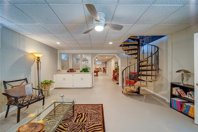 sitting room featuring ceiling fan and a drop ceiling