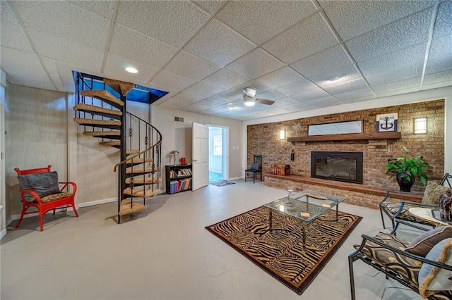 living room featuring a paneled ceiling, a fireplace, and concrete flooring