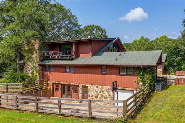 rear view of house featuring a balcony, a garage, and central air condition unit