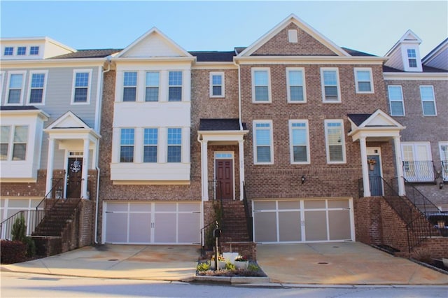 view of property featuring brick siding, driveway, and a garage