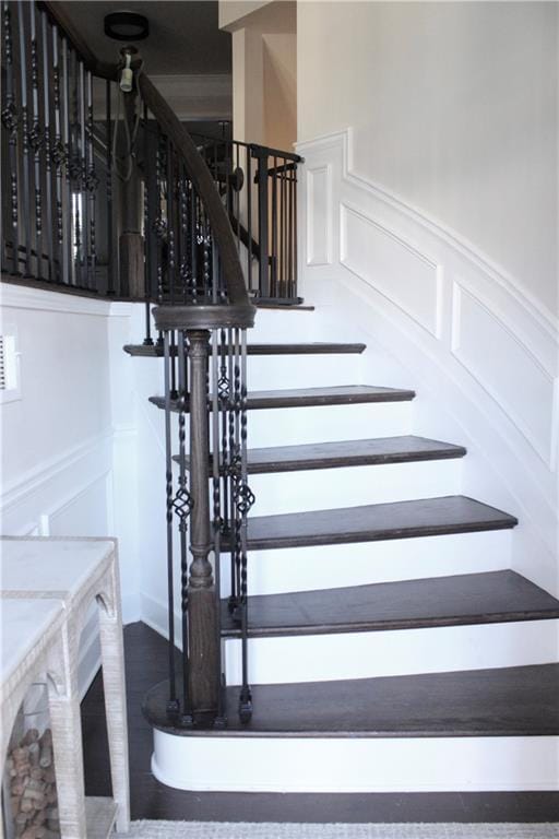 staircase featuring a decorative wall, wood finished floors, and a wainscoted wall