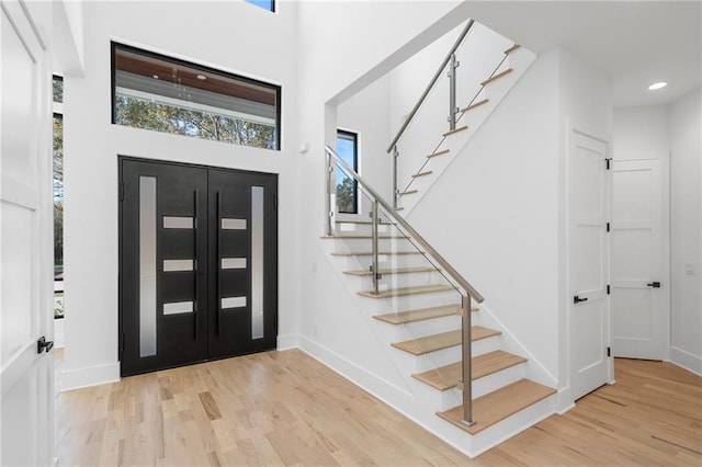 foyer entrance with light hardwood / wood-style flooring and a high ceiling