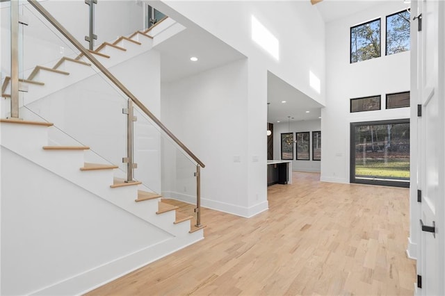 foyer entrance with a towering ceiling and light wood-type flooring