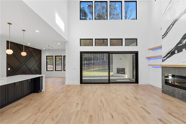 unfurnished living room with a towering ceiling and light hardwood / wood-style floors