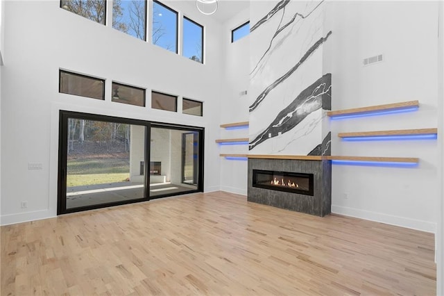 unfurnished living room featuring a tiled fireplace and light hardwood / wood-style floors