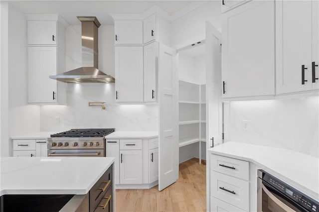 kitchen with light hardwood / wood-style flooring, high end range, backsplash, white cabinetry, and wall chimney exhaust hood