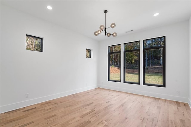 unfurnished room featuring a notable chandelier and light wood-type flooring