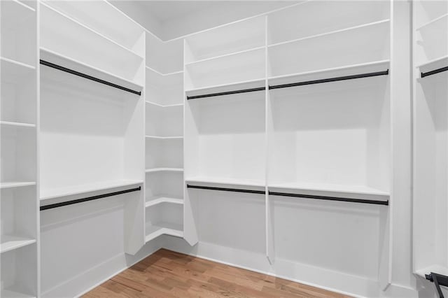 walk in closet with light hardwood / wood-style flooring