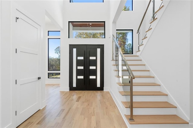 entrance foyer with a towering ceiling and light hardwood / wood-style flooring