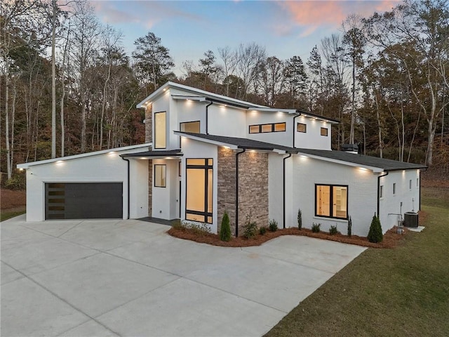 contemporary home featuring a garage, a yard, and central AC unit