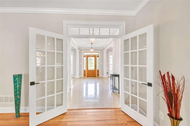 entrance foyer with french doors, ornamental molding, a chandelier, and baseboards