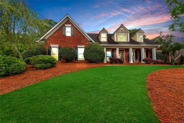 view of front of home featuring a front lawn, covered porch, and brick siding