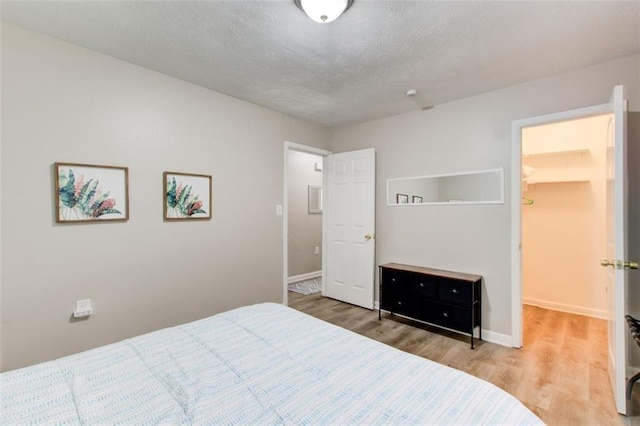1351 Eason St NW, Atlanta, GA 30314 - bedroom with a textured ceiling, light wood finished floors, a walk in closet, and baseboards