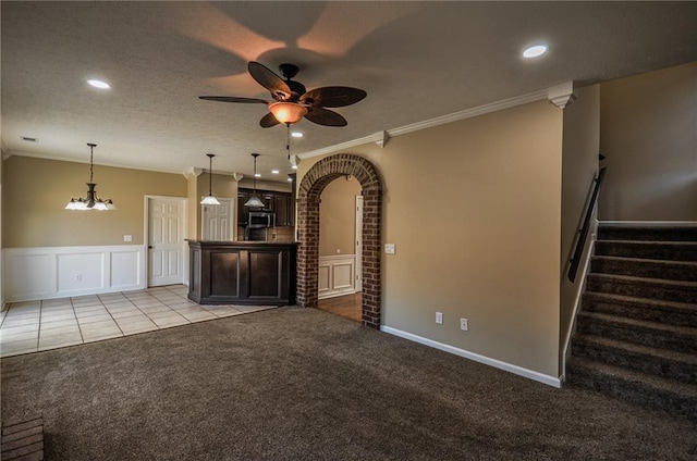 unfurnished living room featuring light colored carpet, ornamental molding, ceiling fan with notable chandelier, and a textured ceiling