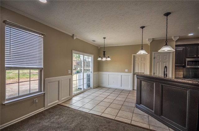 kitchen featuring decorative light fixtures, light tile patterned floors, a notable chandelier, crown molding, and a textured ceiling