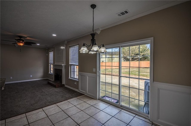 unfurnished dining area featuring crown molding, light colored carpet, and ceiling fan with notable chandelier