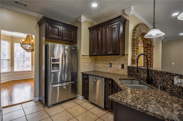 kitchen featuring dark brown cabinetry, sink, decorative light fixtures, ornamental molding, and stainless steel appliances