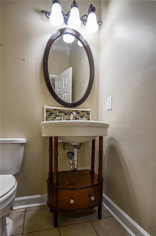 bathroom with toilet, tile patterned flooring, and decorative backsplash