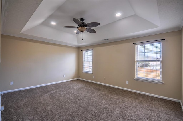 empty room featuring ceiling fan, a tray ceiling, and carpet