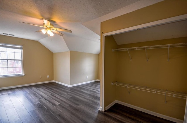 additional living space featuring ceiling fan, vaulted ceiling, dark wood-type flooring, and a textured ceiling