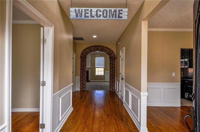 hallway with crown molding, dark wood-type flooring, and a textured ceiling