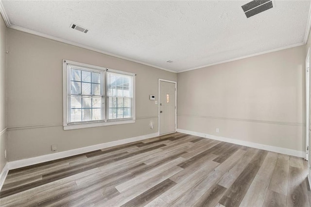 empty room with hardwood / wood-style floors, ornamental molding, and a textured ceiling