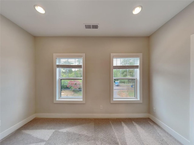 unfurnished room with plenty of natural light, light colored carpet, baseboards, and visible vents