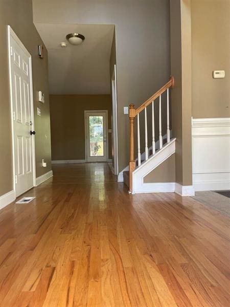 foyer featuring stairway, baseboards, visible vents, and wood finished floors