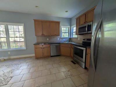 kitchen with decorative backsplash, baseboards, and appliances with stainless steel finishes