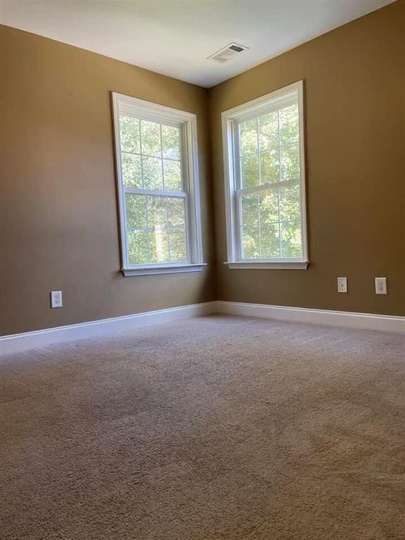 carpeted empty room featuring baseboards and visible vents