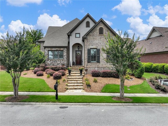 5964 Chickasaw Ln, Braselton, GA 30517 - french provincial home with stucco siding, a shingled roof, stone siding, and a front lawn