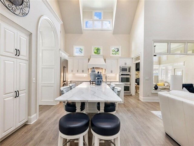 5964 Chickasaw Ln, Braselton, GA 30517 - kitchen featuring a high ceiling, tasteful backsplash, a kitchen bar, light wood-type flooring, and stainless steel appliances