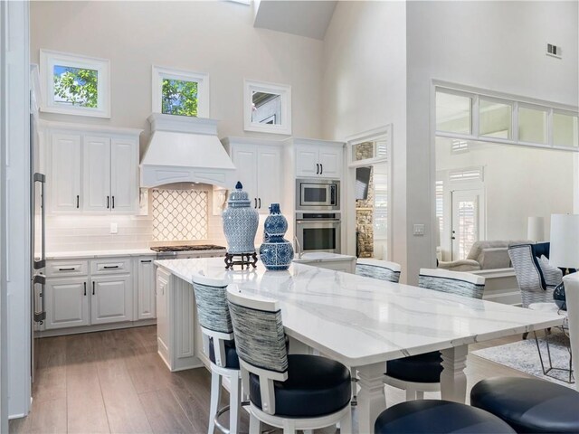 5964 Chickasaw Ln, Braselton, GA 30517 - kitchen with a high ceiling, wood finished floors, visible vents, stainless steel appliances, and custom range hood