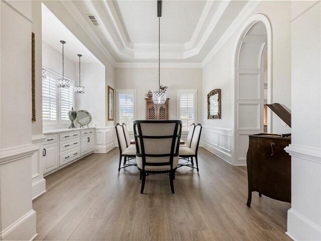 5964 Chickasaw Ln, Braselton, GA 30517 - dining area with light wood-style flooring, an inviting chandelier, a raised ceiling, a decorative wall, and wainscoting