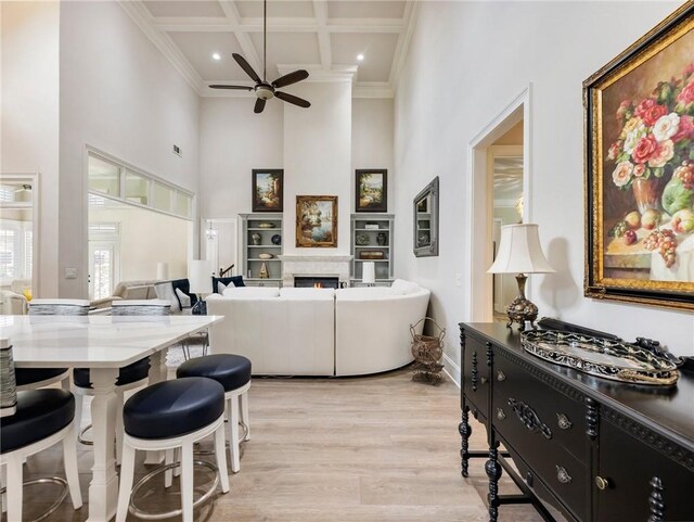 5964 Chickasaw Ln, Braselton, GA 30517 - living room with coffered ceiling, a towering ceiling, a lit fireplace, light wood finished floors, and ceiling fan