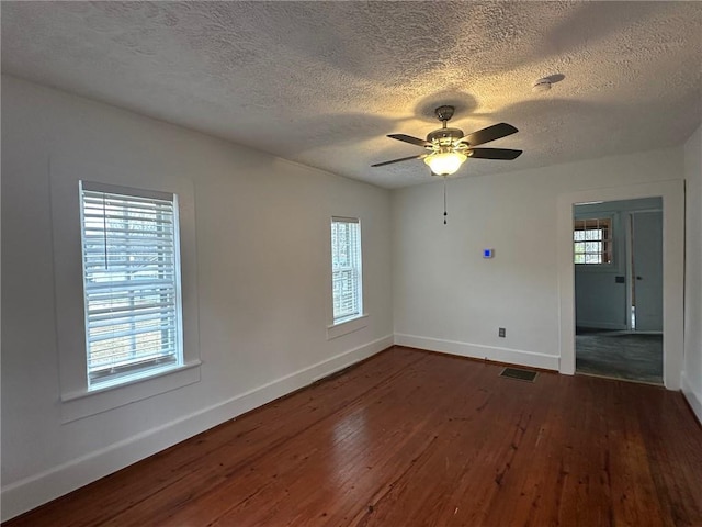 empty room with dark wood-style floors, plenty of natural light, a ceiling fan, and baseboards