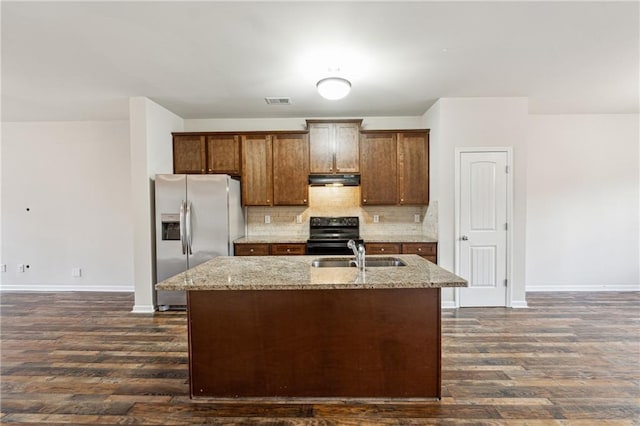 kitchen featuring stainless steel refrigerator with ice dispenser, sink, light stone counters, electric range, and a kitchen island with sink