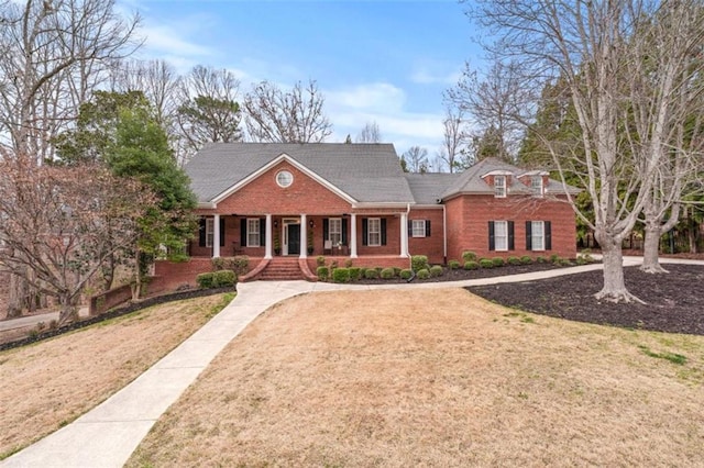 view of front of home with covered porch, brick siding, and a front lawn