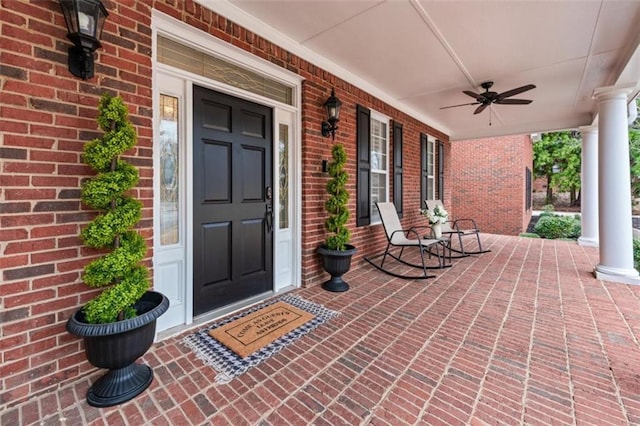 view of exterior entry with covered porch, brick siding, and ceiling fan