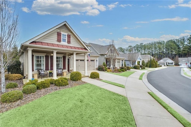 view of front facade featuring metal roof, covered porch, driveway, a standing seam roof, and a front yard