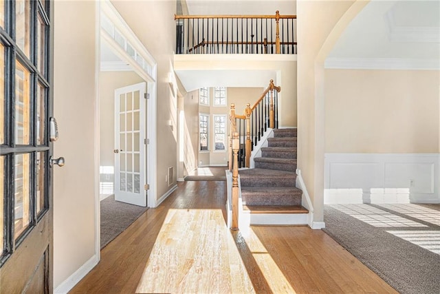 entryway featuring french doors, wood finished floors, a high ceiling, and crown molding