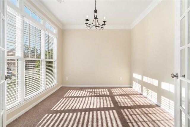 carpeted empty room with french doors, a notable chandelier, crown molding, and baseboards