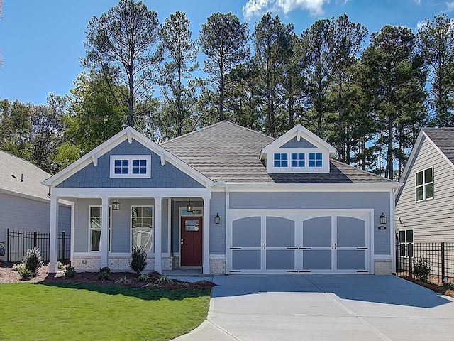 craftsman-style house featuring a porch, a front yard, and a garage