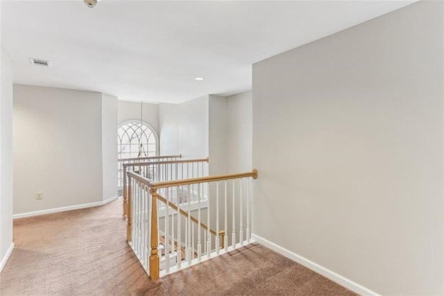 corridor featuring carpet, visible vents, an upstairs landing, and baseboards