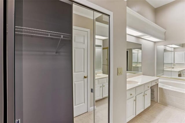 bathroom featuring two vanities, a sink, tile patterned flooring, a bath, and a spacious closet