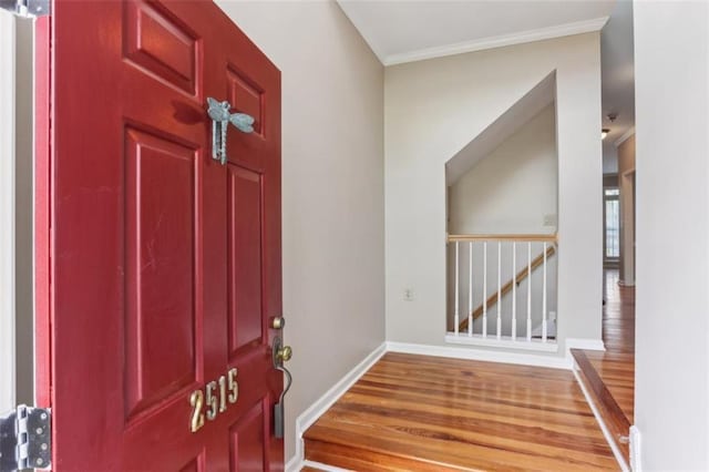 entrance foyer featuring baseboards, wood finished floors, and crown molding